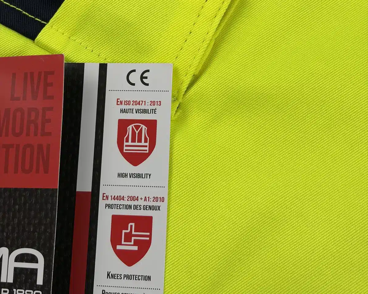 Pantalon haute visibilité jaune LMA avec son étiquette carton : pictogramme EN ISO 20471 haute visibilité et EN 14404 protection des genoux